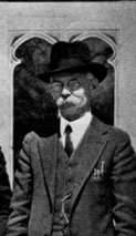 Black and white photo of a man wearing a suit and a hat.
