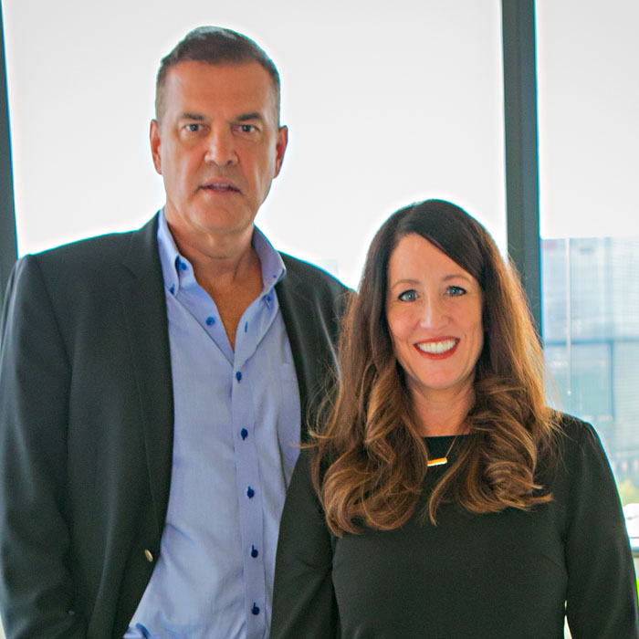 portrait of professional looking woman and man in front of windows