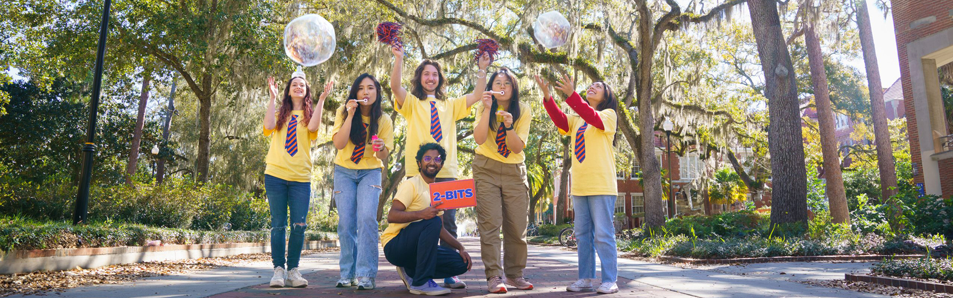 Kids in yellow shirts and blue and orange ties celebrating with party favors