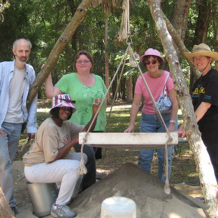 picture of group of people standing around a pile of sand