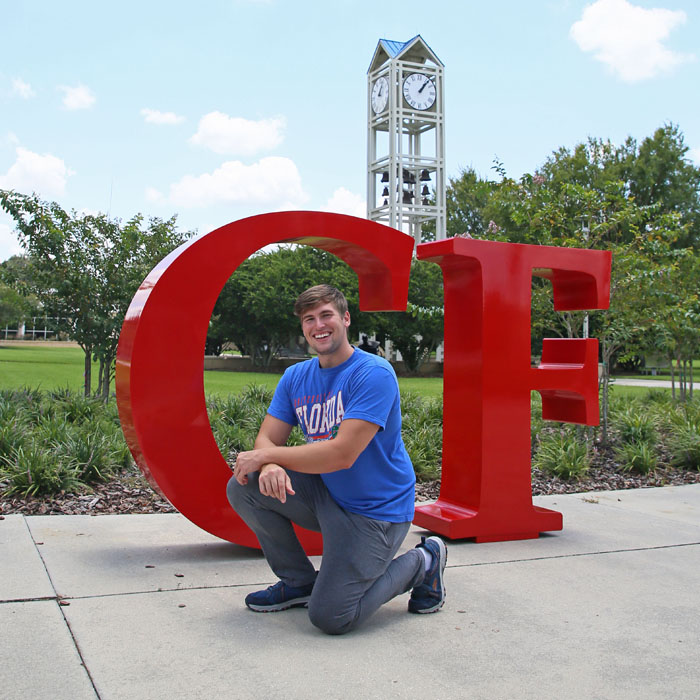 picture of man kneeling in front of a giant C and F